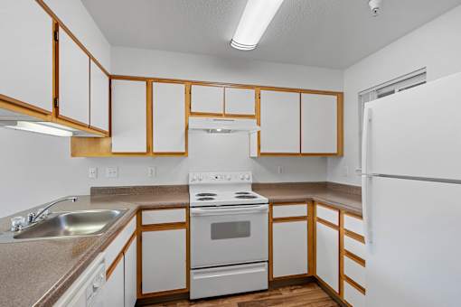 an empty kitchen with white appliances and wooden cabinets at Summer Creek Apartments, Tigard