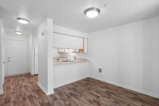 an empty living room and kitchen with white walls and wood floors at Summer Creek Apartments, Tigard