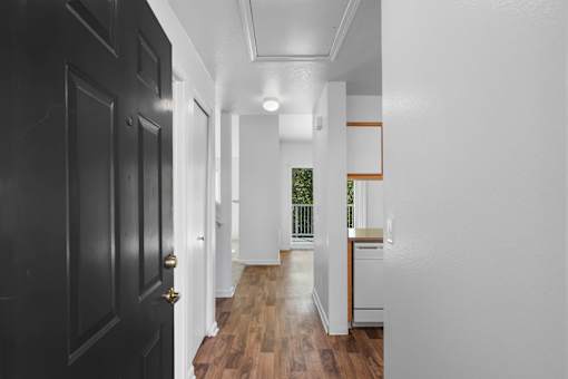 a hallway with black doors and white walls and a kitchen at Summer Creek Apartments, Tigard, OR, 97223