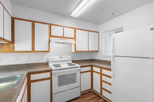 a kitchen with white appliances and wooden cabinets at Summer Creek Apartments, Tigard, OR