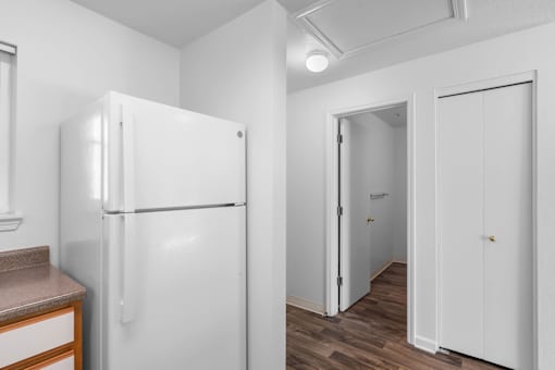 a white kitchen with a refrigerator and a door to a hallway at Summer Creek Apartments, Tigard, 97223