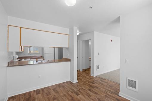 an empty living room and kitchen with white walls and wood floors at Summer Creek Apartments, Tigard, Oregon