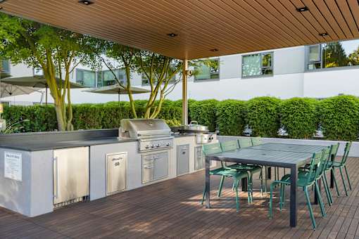 the outdoor kitchen has stainless steel appliances and a table with chairs