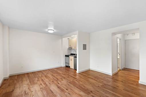 a living room and kitchen with wood floors and white walls