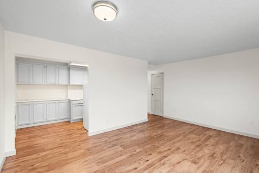 an empty living room with wood flooring and white walls