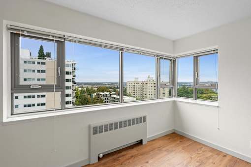 an empty room with windows and a radiator and a city view