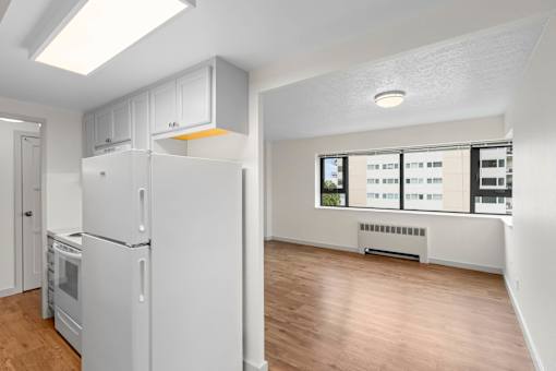 an empty living room with a refrigerator and a window