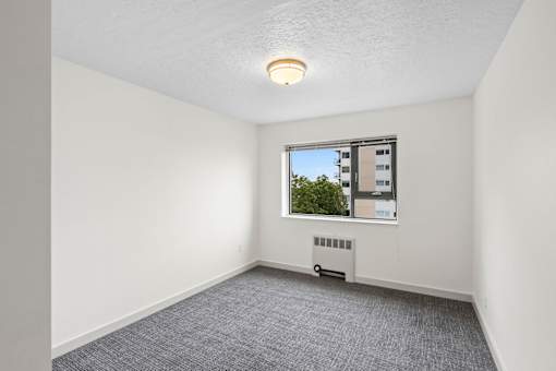 an empty living room with a window and white walls