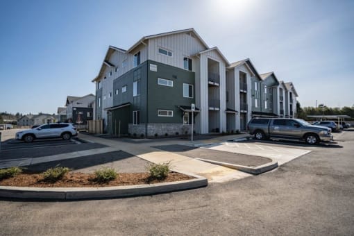 an apartment building with cars parked in a parking lot at Sonder Fields in Happy Valley, OR