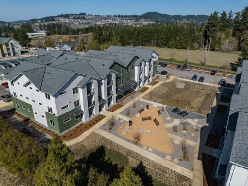 an aerial view of an apartment building with green and white buildings and a parking lot at Sonder Fields in Happy Valley, OR