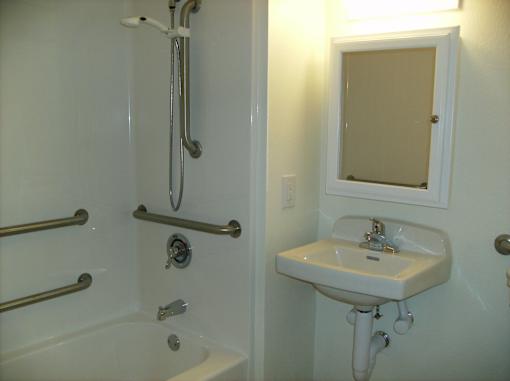 A white sink is on a white pedestal in a white bathroom.