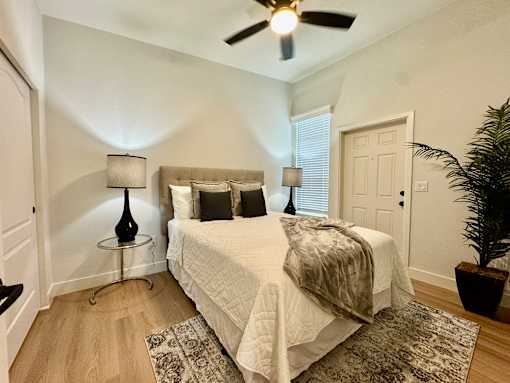 A bedroom with a bed, two lamps, and a ceiling fan.
