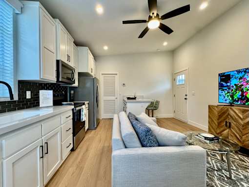 A modern kitchen with a grey couch and a ceiling fan.