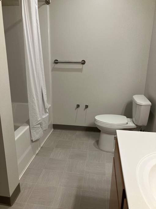 A white toilet sits in a bathroom next to a white sink.