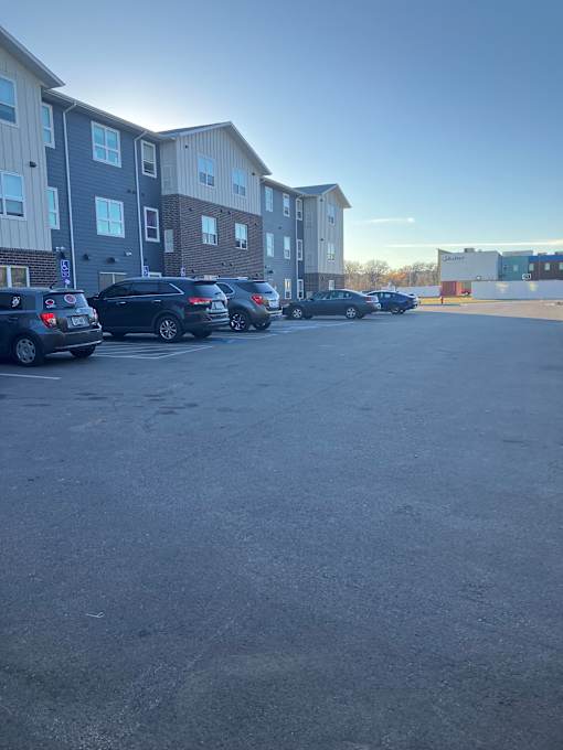 A parking lot with several cars and apartment buildings in the background.