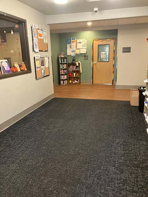 A room with a carpeted floor and a bookshelf.