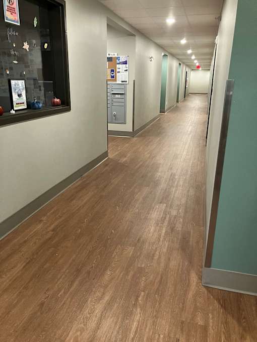 A long hallway with wood floors and white walls.
