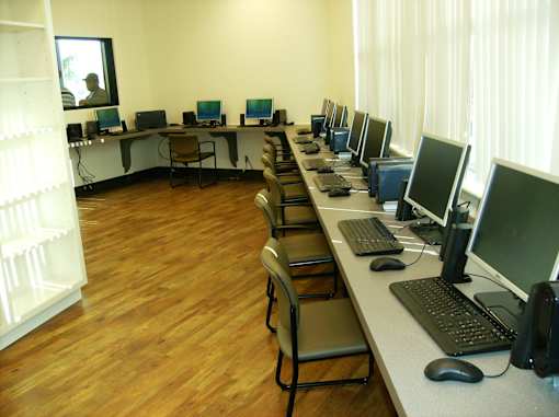 A room with a long table and chairs with multiple monitors on the table.