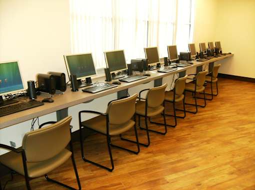 A long table with chairs and computers on it.