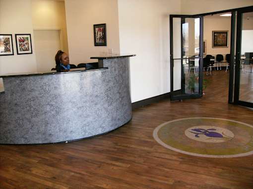 A receptionist is behind the desk in a well lit office.