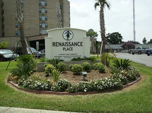 A sign for Renaissance Place, a senior living community, is surrounded by a flower bed.