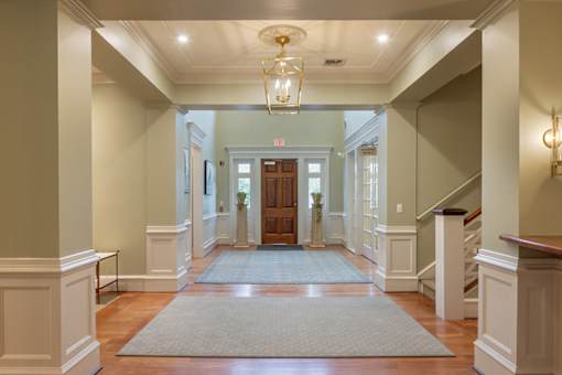 A hallway with a rug on the floor and a chandelier hanging from the ceiling.