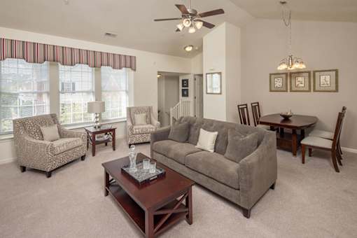 A living room with a grey couch, a coffee table, and a ceiling fan.