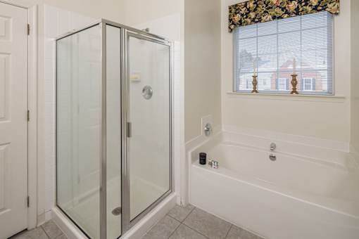 A white bathroom with a glass shower stall and a white bathtub.
