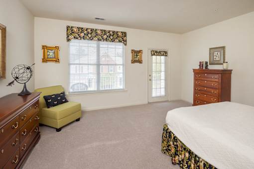 A bedroom with a bed, dresser, and chair.