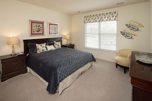 A bedroom with a bed, nightstands, and a chair.