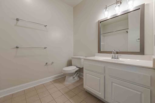 A bathroom with a toilet, sink, and mirror.