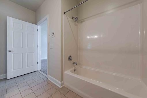 A white bathroom with a tub and a door.