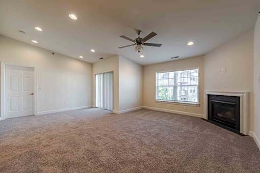 A spacious living room with a fireplace and a ceiling fan.