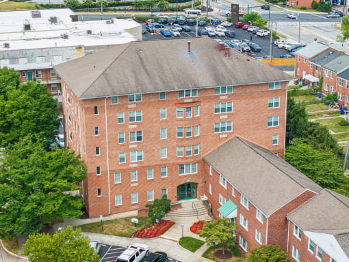an aerial view of a brick building with trees and a parking lot