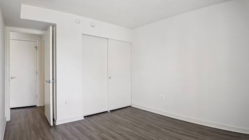 A room with a white door and two white closet doors.