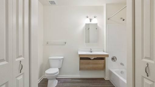 A white bathroom with a toilet, sink, and mirror.