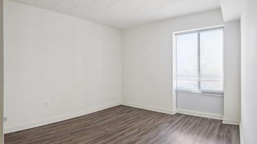 Empty room with wooden flooring and a window.