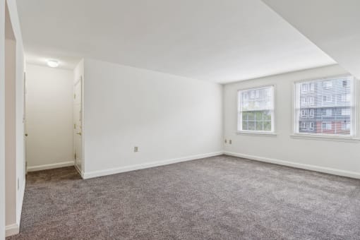 a living room with carpet and two windows