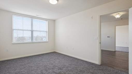 A room with a large window and a carpeted floor.