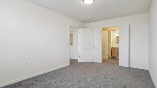 A room with white walls and a grey carpet.