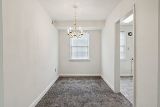 an empty living room with a chandelier and a window