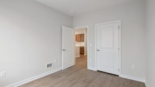 A room with two white doors and a wooden floor.