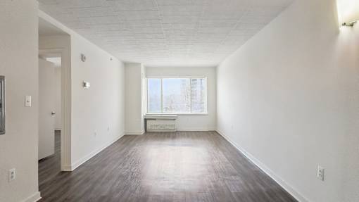A large empty room with a window and a white couch.