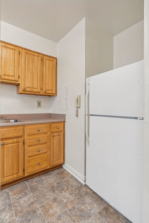 a kitchen with a white refrigerator and wooden cabinets