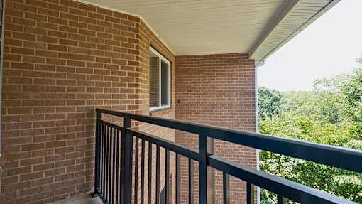 A balcony with a black railing and a brick wall.