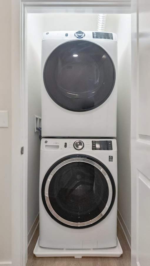 A white front load washing machine with a black door is in a white doorway.