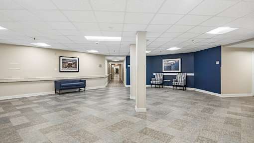 A spacious room with a bench, chairs, and a painting on the wall.