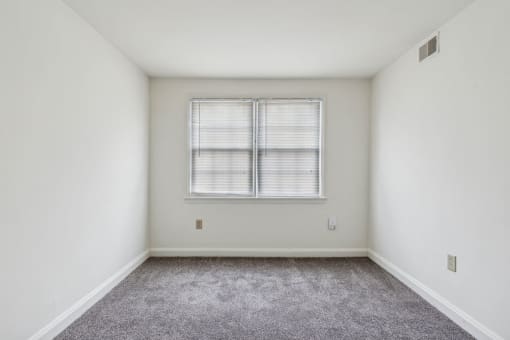 an empty room with white walls and a window