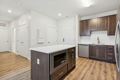 A kitchen with a white counter top and wooden floors.