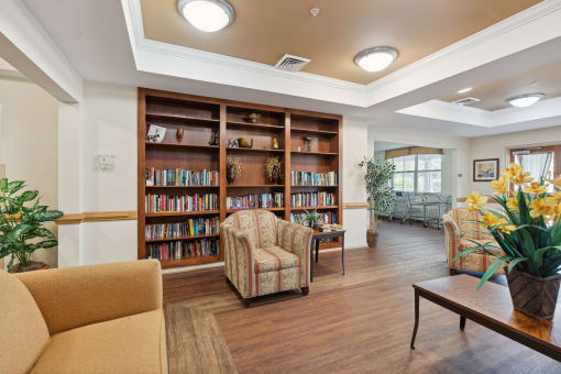 a seating area with couches and chairs and a bookshelf with books
